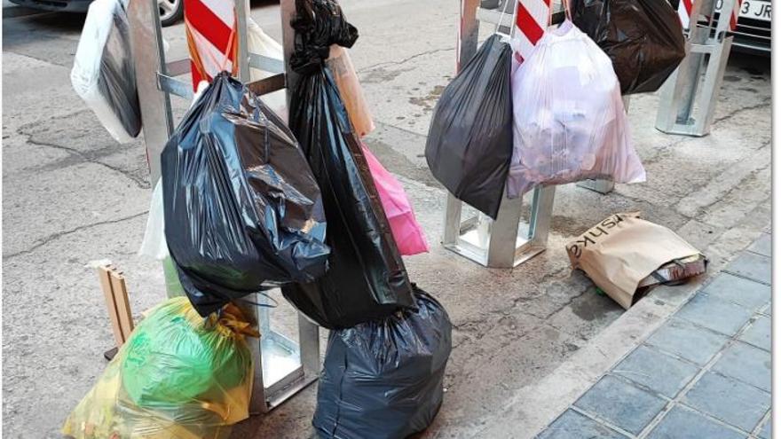 Bolsas de basura colgados de los totems donde deberían ir los cubos en Meliana, en señal de protesta.