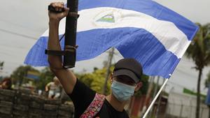  Un joven manifestante alza su arma artesanal y la bandera nacional de Nicaragua contra el régimen de Ortega.