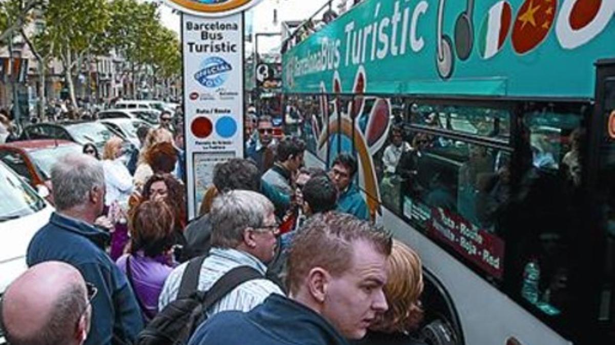 Turistas a punto de tomar el bus frente a la Pedrera.