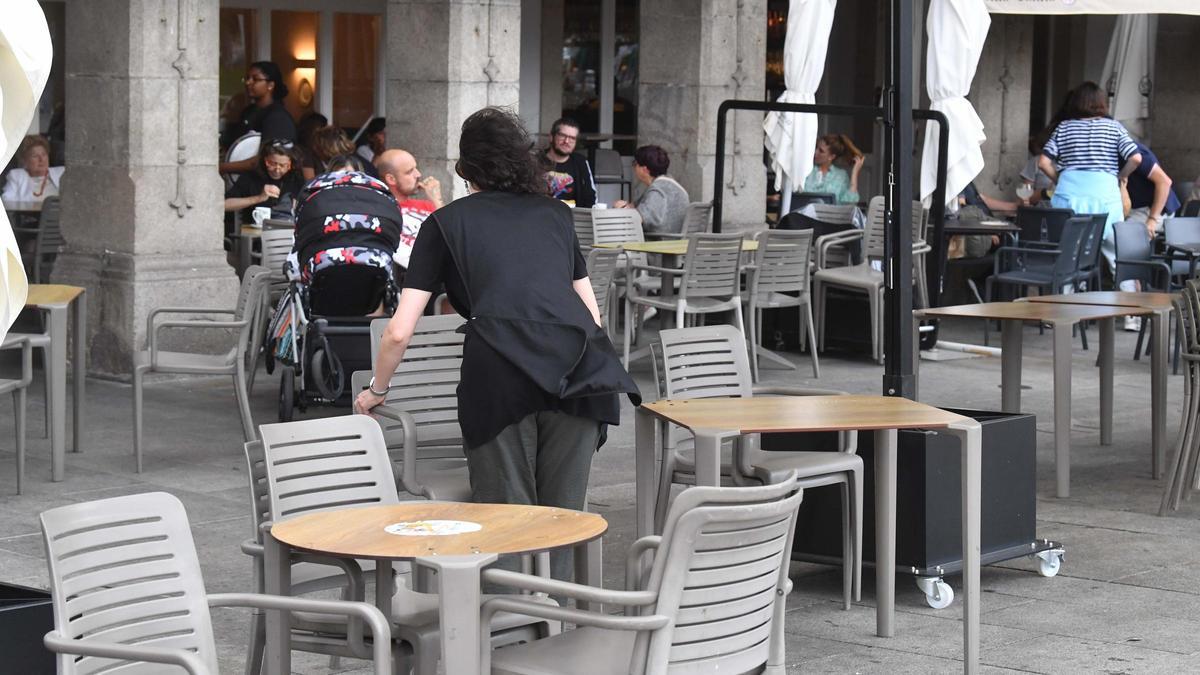 Una camarera recoge las sillas de una terraza de la Marina