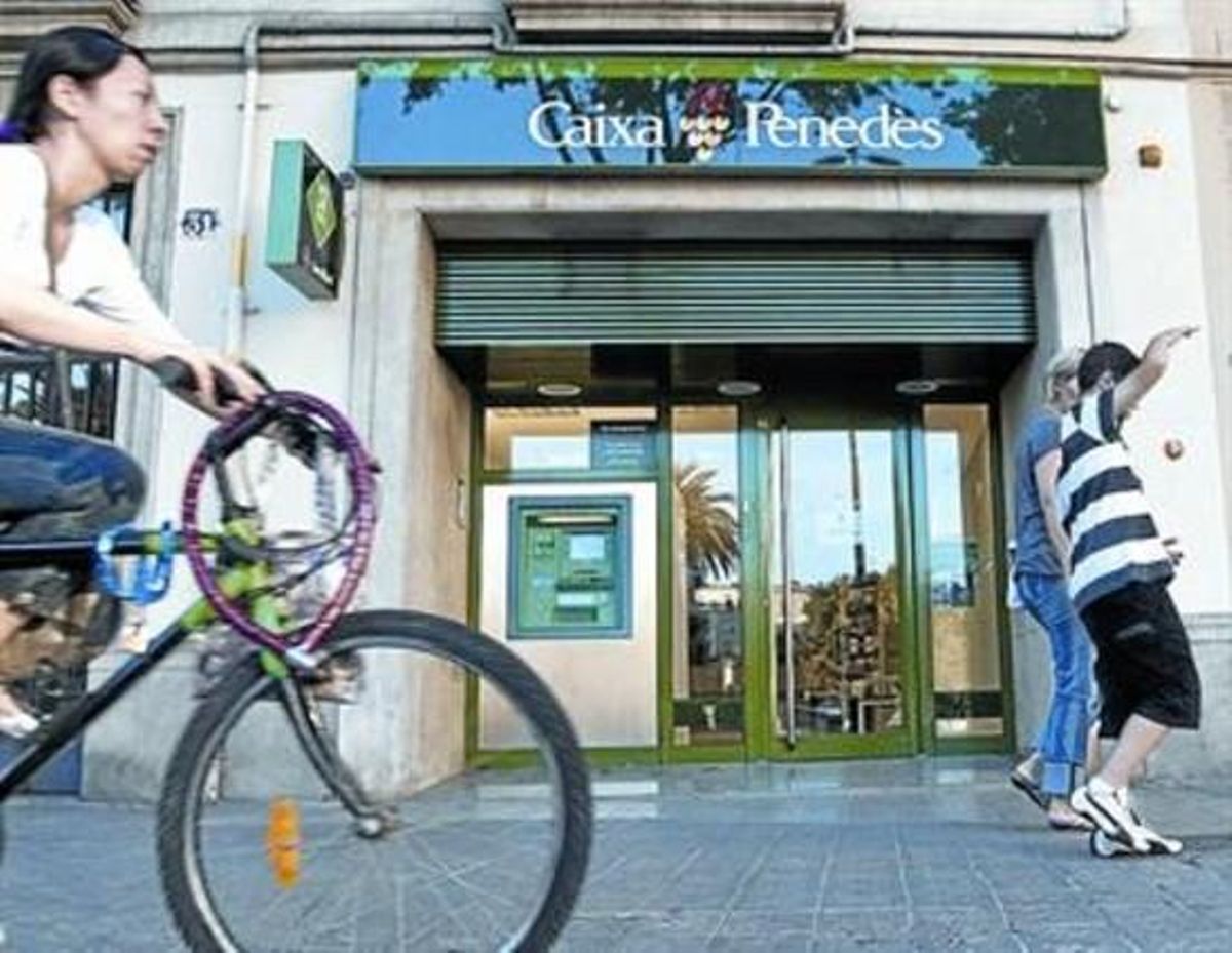 En trànsit. Uns vianants circulen davant una sucursal de Caixa Penedès a Barcelona, ahir.