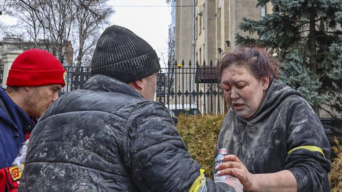 Un persona entregando una botella de agua a una víctima tras los bombardeos del ejército ruso