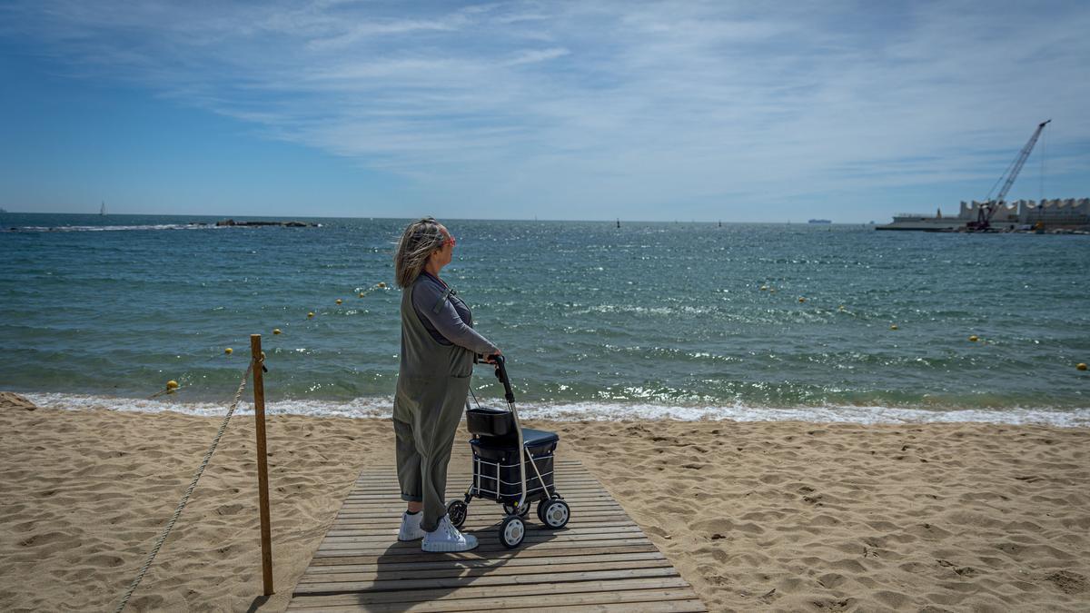 Lydia García Modrego, con un andador, junto a la orilla en la playa de Nova Icària, en Barcelona.