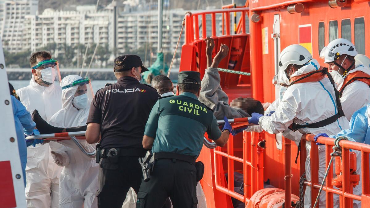 Los agentes ayudan a unos inmigrantes a su llegada a Arguineguín.