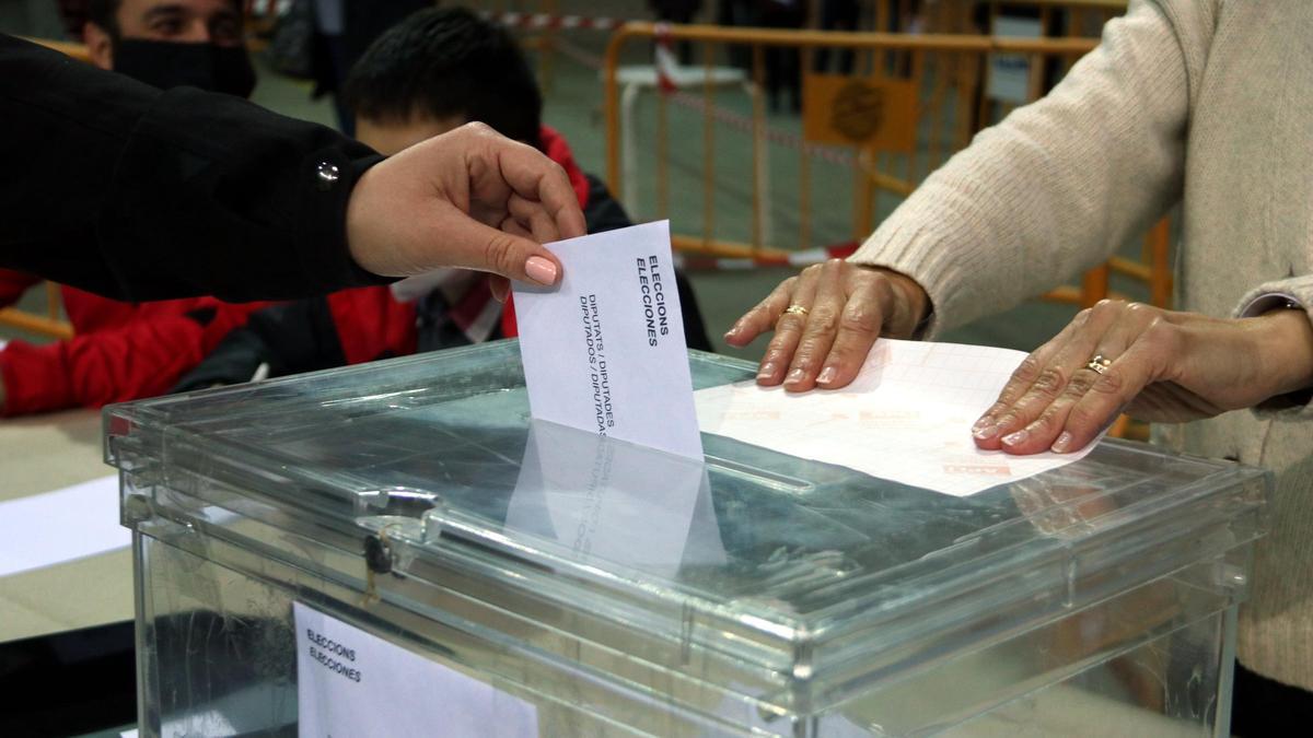 Una urna i de la mà d'una persona votant en un col·legi electoral
