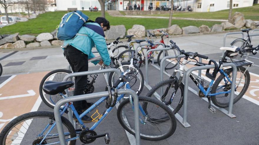 Un aparcament de bicicletes de Girona i un usuari lligant-hi la seva