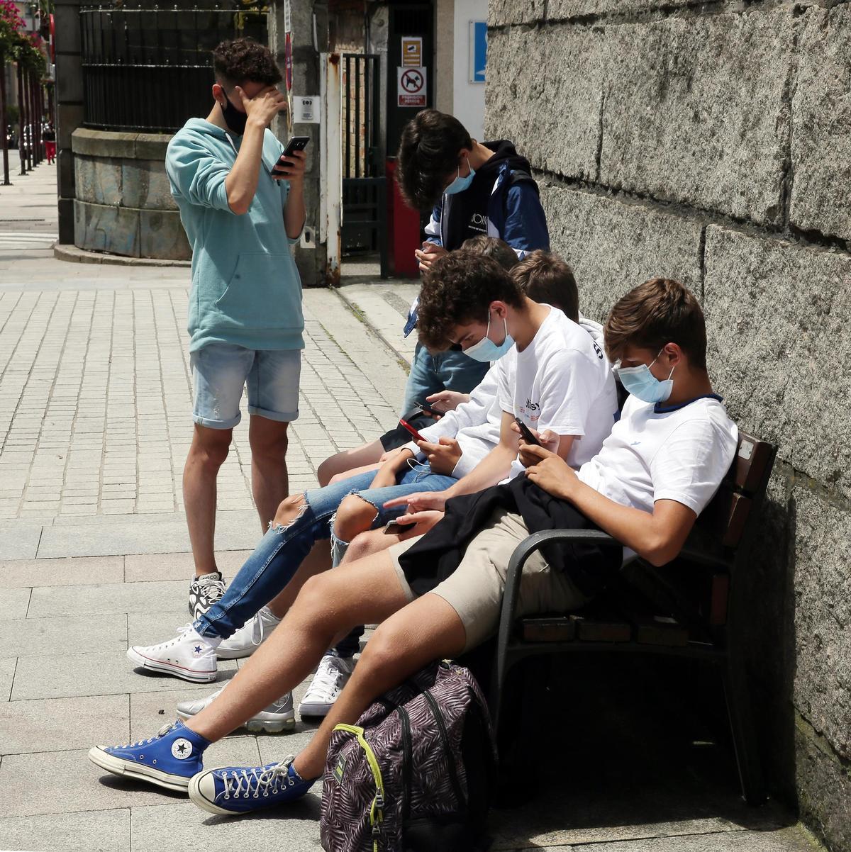 ALUMNOS SALIENDO DEL CENTRO EDUCATIVO EL UTLIMO DIA DE CLASE ANTES DE LAS VACACIONES. JOVENES CON SUS MOVILES.
