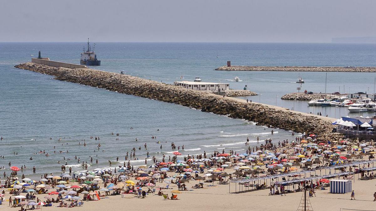 Bañistas en la arena de la playa, la escollera y la bocana del puerto de Gandia. | LEVANTE-EMV