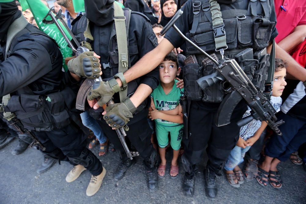 Palestinian boys stand next to Hamas militants ...