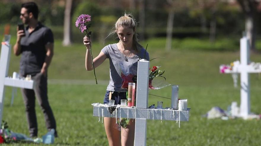 Una joven deposita flores en el memorial por las víctimas