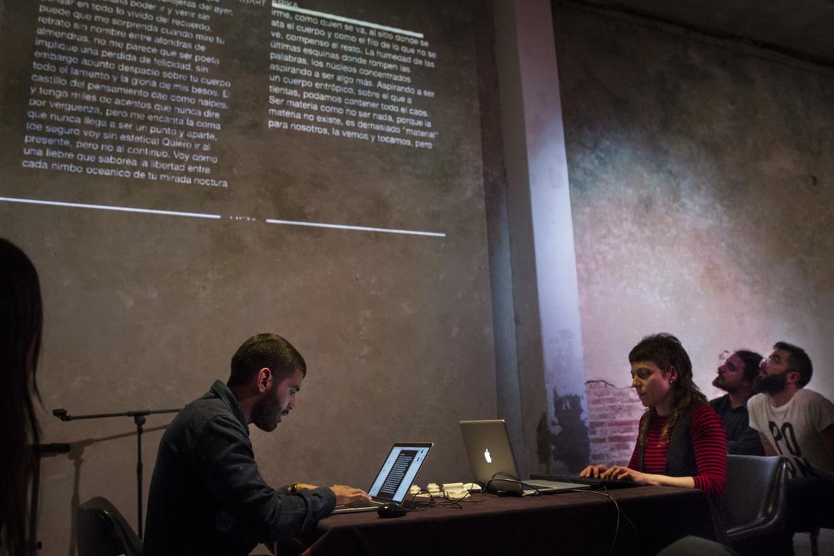 Alexander Martínez y Erika Rubio improvisan sobre el teclado durante la carrera literaria del VI Slam de Escritura, en el centro de arte Mutuo. Proyectados en la pared, los textos que están escribiendo.    