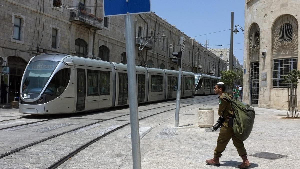 Un soldado israelí camina por la calle de Jaffa ante el tranvía de Jerusalén.