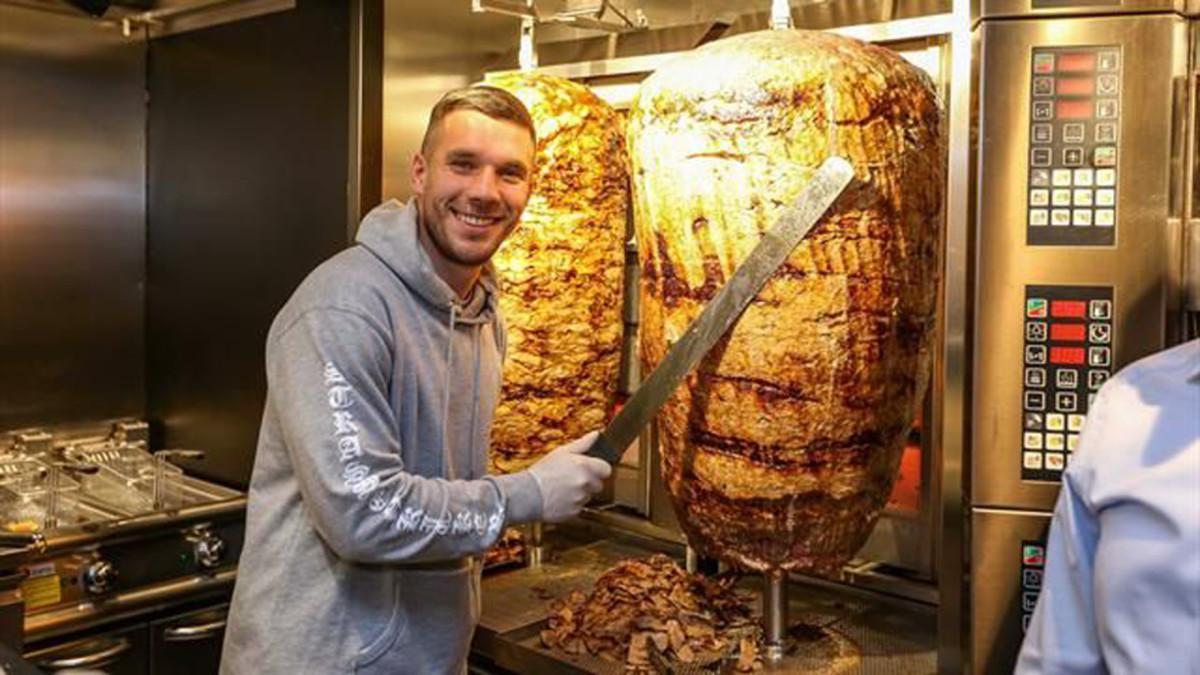 Lukas Podolski corta una pieza de carne en su 'Döner Kebab'