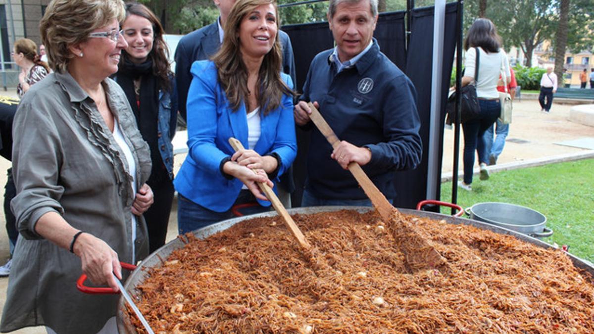 Alicia Sánchez-Camacho (centro) y Alberto Fernández Díaz colaboran en la preparación de una fideuà popular, este sábado en el distrito de Les Corts.