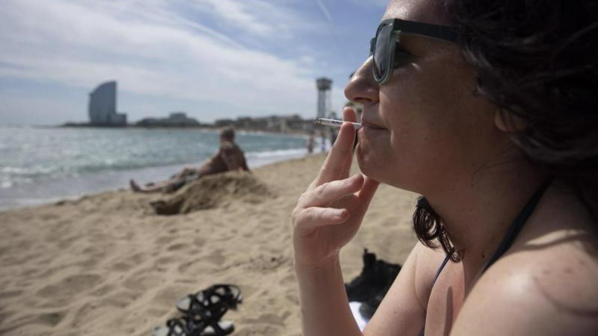 Barcelona 8/04/2022 Día de playa en la Barceloneta el día antes que se inicie la temporada de playas En la foto, una mujer fuma en la playa Foto de Ferran Nadeu