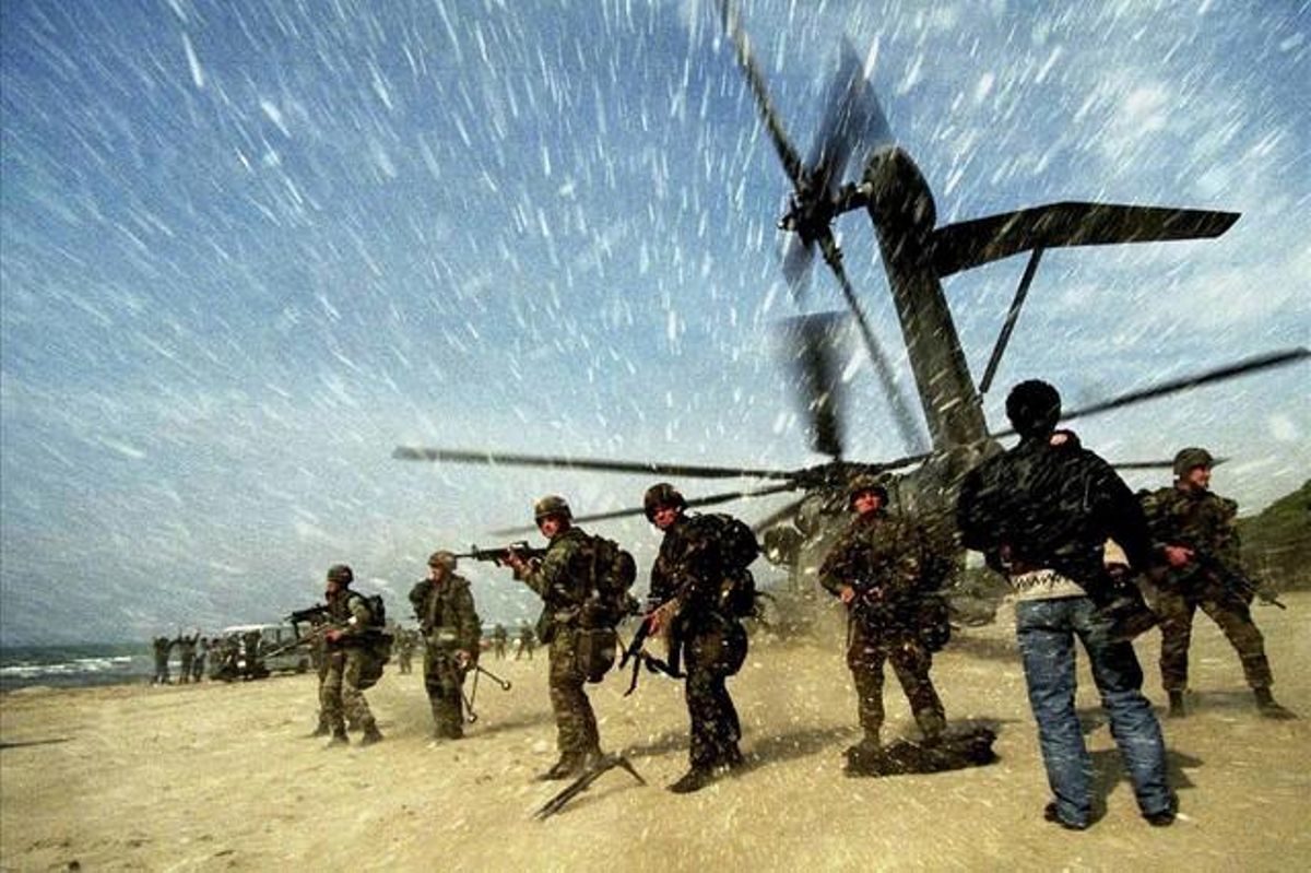 An Albanian man carries a child to a US Marine CH53 Super Stallion helicopter as it lands at Golame beach near the port of Durrës, in this March 16, 1997 file picture.