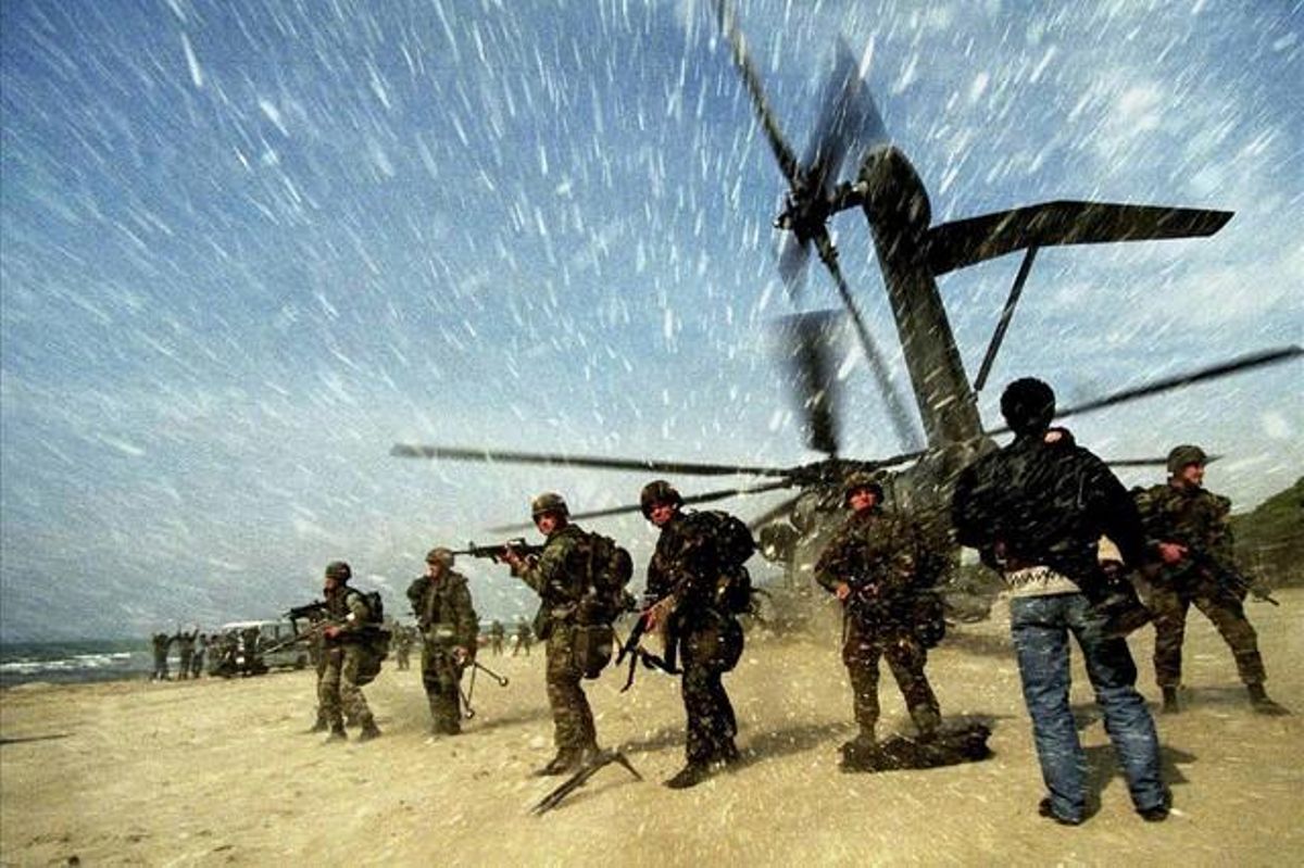 An Albanian man carries a child to a US Marine CH53 Super Stallion helicopter as it lands at Golame beach near the port of Durres, in this March 16, 1997 file picture.