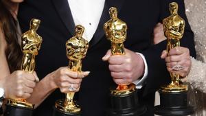 Cuatro premiados con los Oscar muestran sus estatuillas.