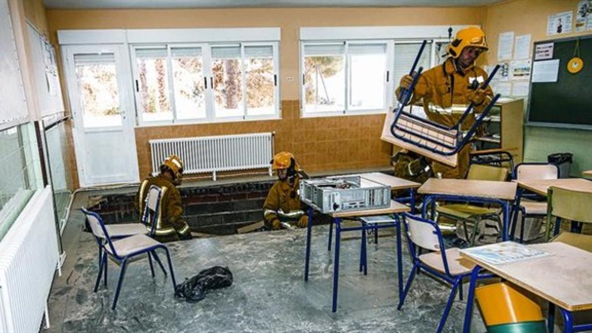 Los bomberos trabajan en el aula afectada, cuyo suelo se hundió en parte ayer, en Alicante.