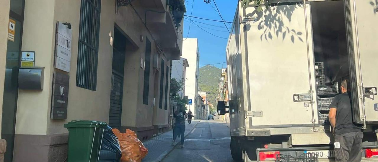 L&#039;entrada del bloc de pisos del carrer Pecher, rodejada d&#039;escombraries i amb un camió al davant.