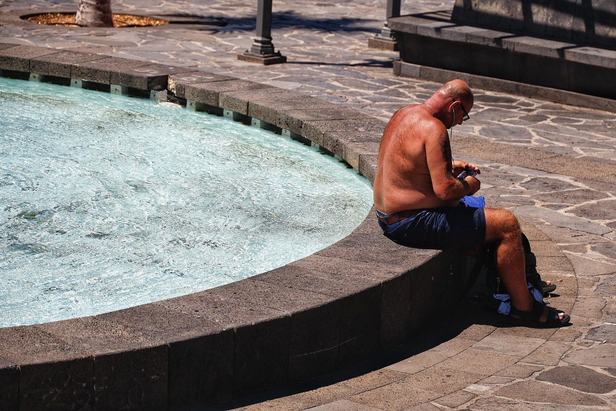 Un hombre sin camiseta sentado junto a una fuente en Santa Cruz de Tenerife.