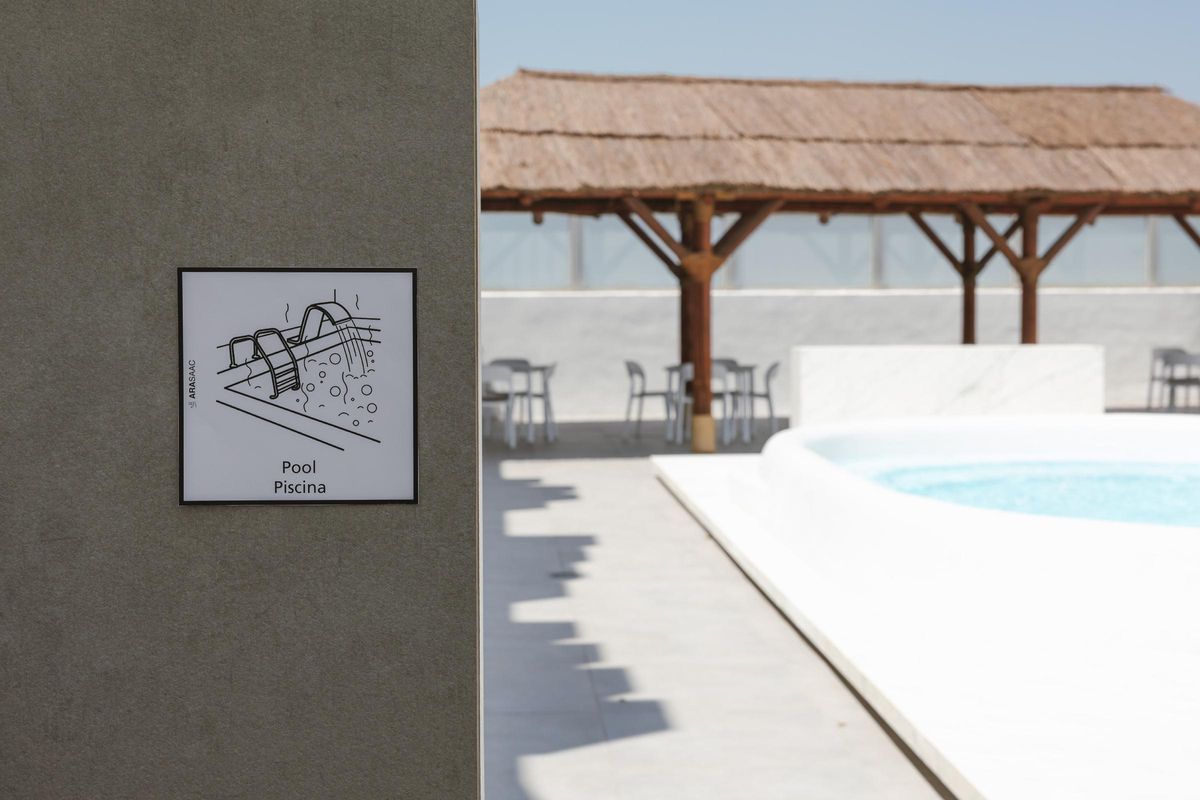 Fijación de uno de los carteles descriptivos instalados junto a la piscina