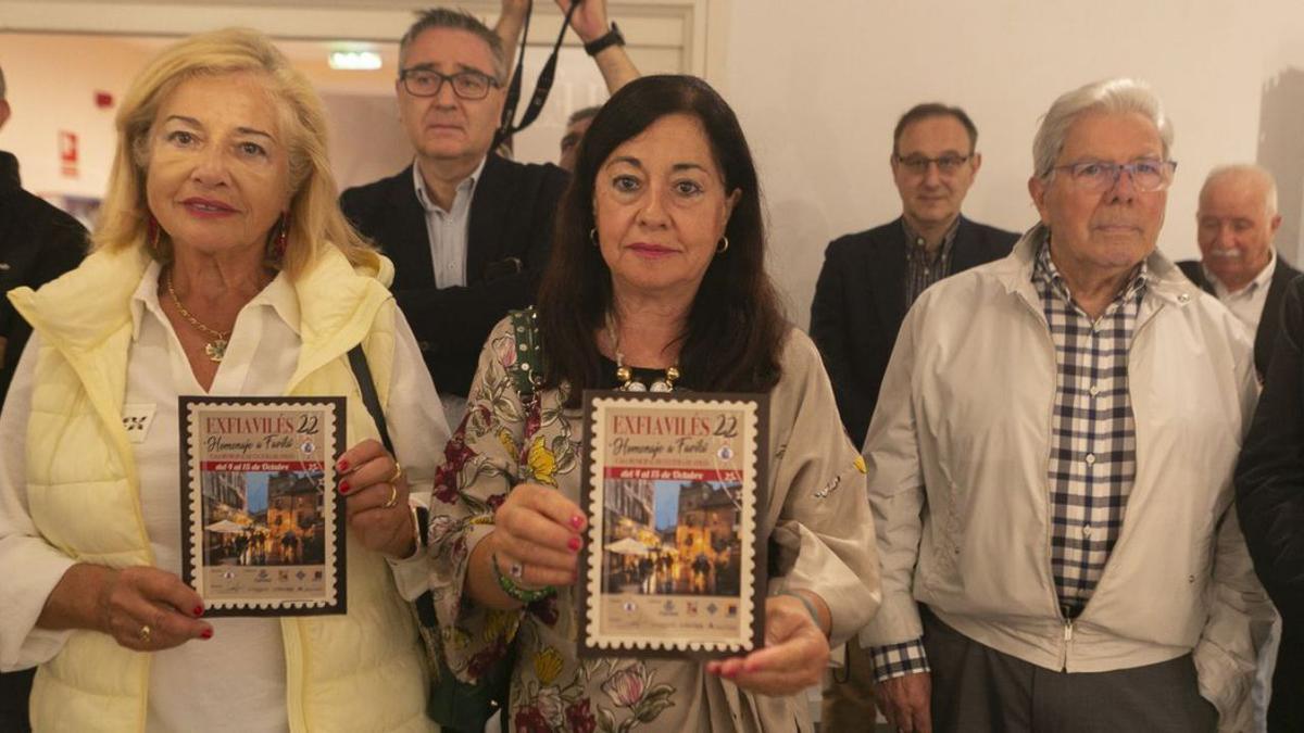 Participantes en ExfiAvilés muestran un detalle del sello y la tarjeta postal de esta edición, que reproducen una de las obras de Favila. | María Fuentes