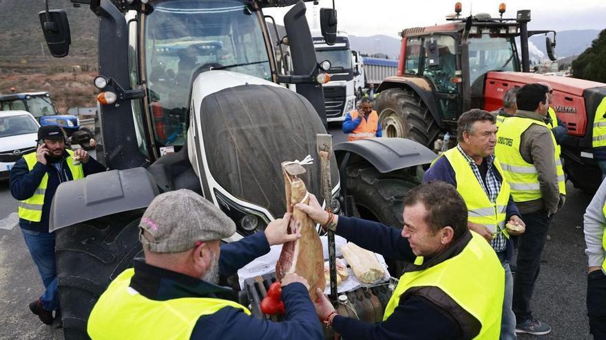 Los agricultores cortan
jamón encima de uno de
de los tractores.  Iván Urquízar