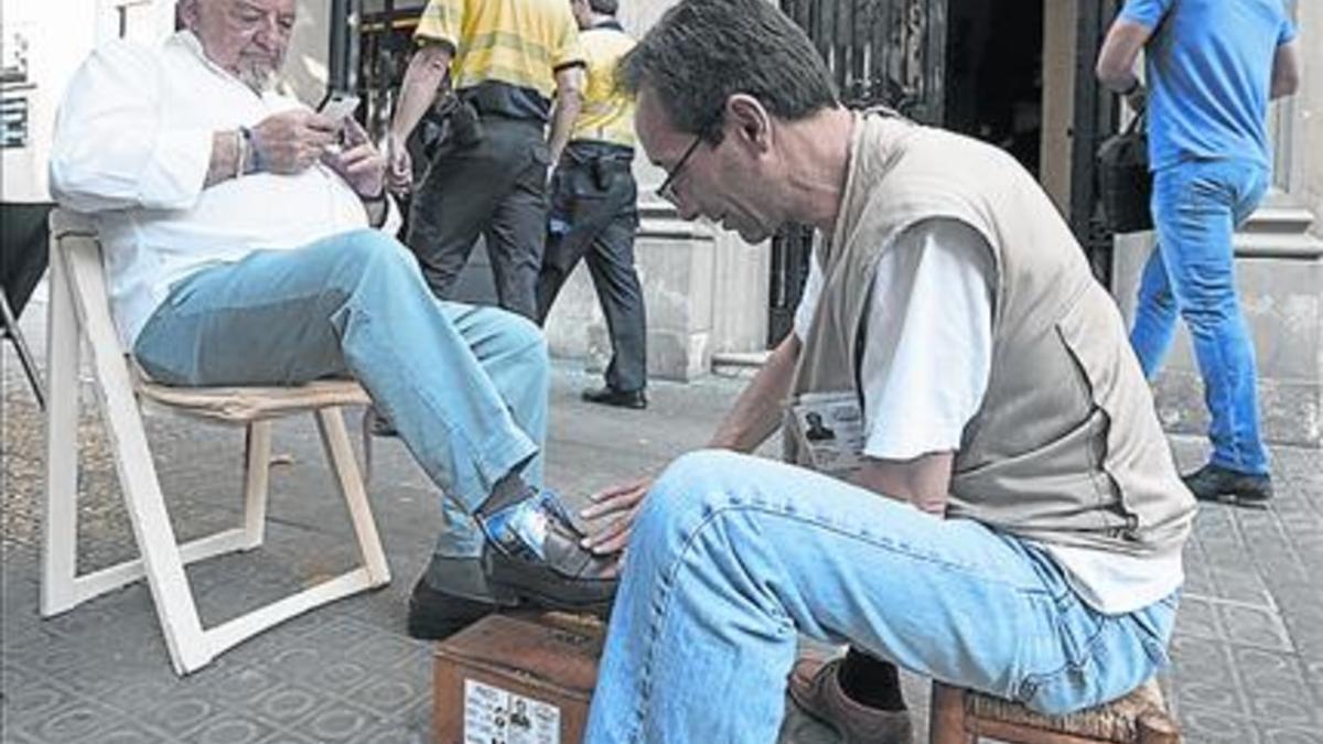 En la terraza 8 Fernando Rodríguez limpia los zapatos a un cliente.