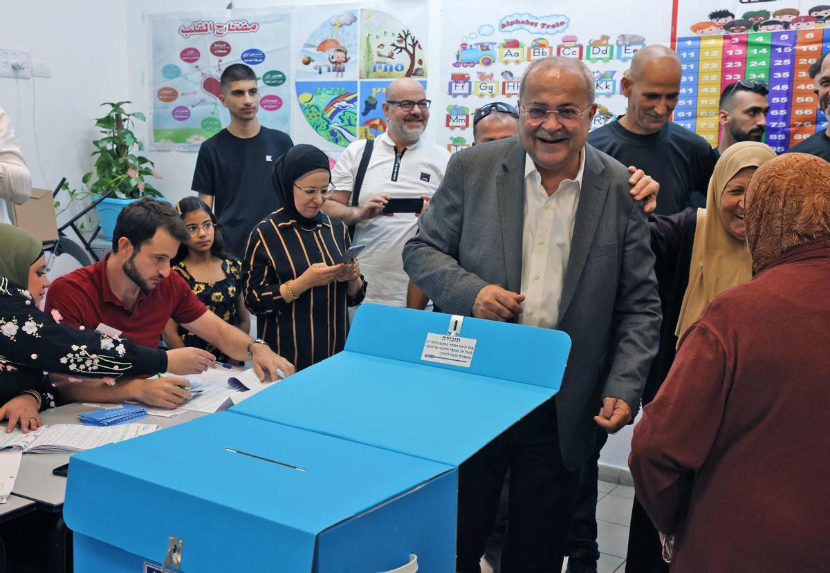 Ahmad Tibi (C-R), jefe del partido Movimiento Árabe para el Cambio (Ta’al), se para detrás de una urna en un colegio electoral en la ciudad predominantemente árabe de Taybeh en el centro de Israel durante las elecciones nacionales.