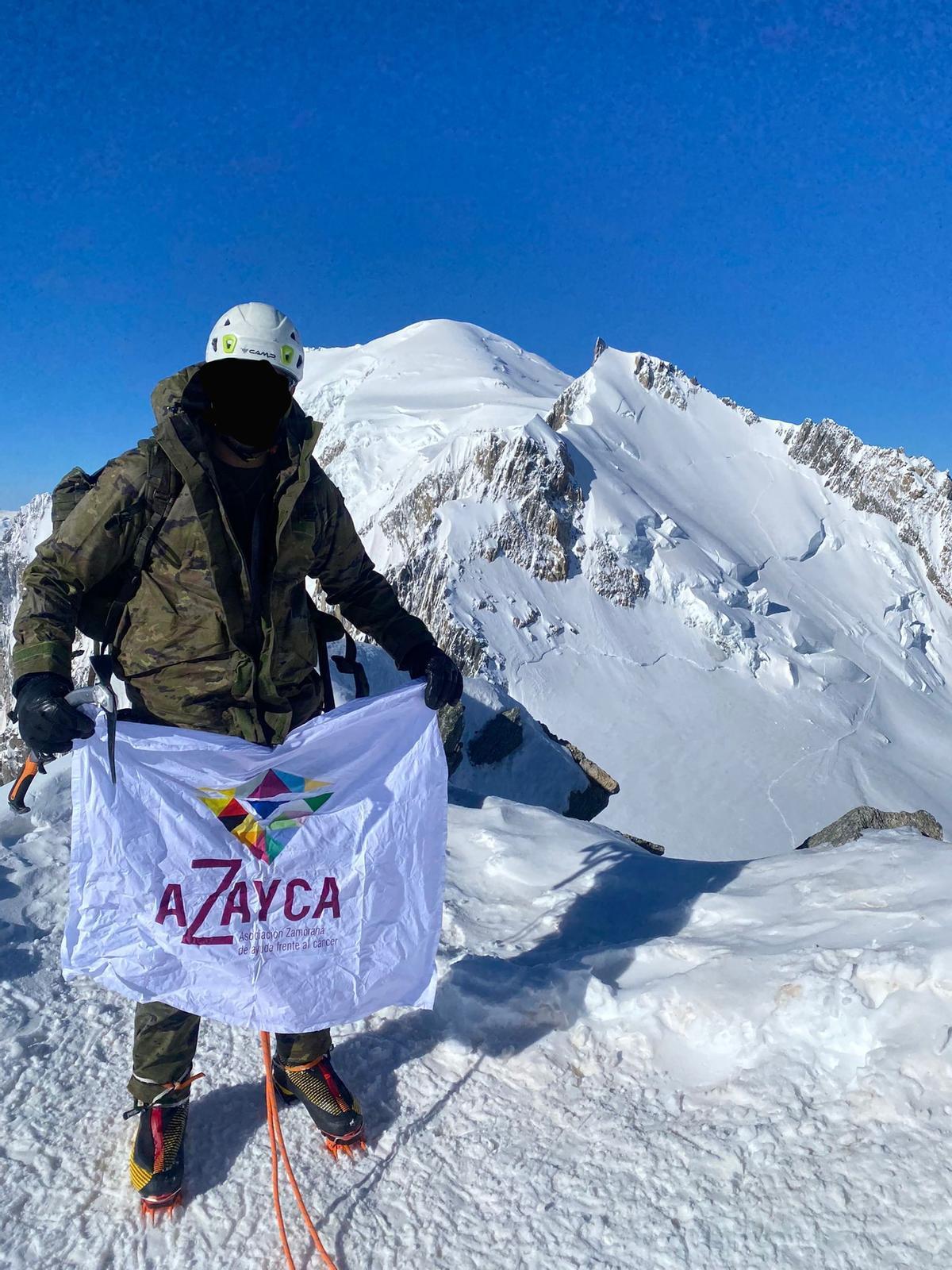 El montañero, con la bandera de Azayca en los Alpes