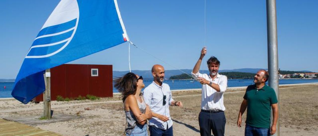 El alcalde Varela y los concejales Diego García, Álvaro Carou y Alba Briones izan la bandera azul en la playa Compostela, ayer.