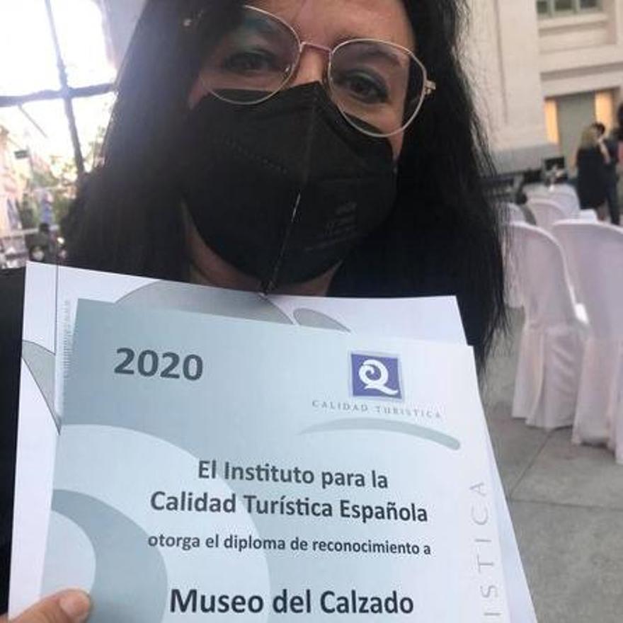 Loles Esteve mostrando el título conseguido por el Museo del Calzado de Elda.