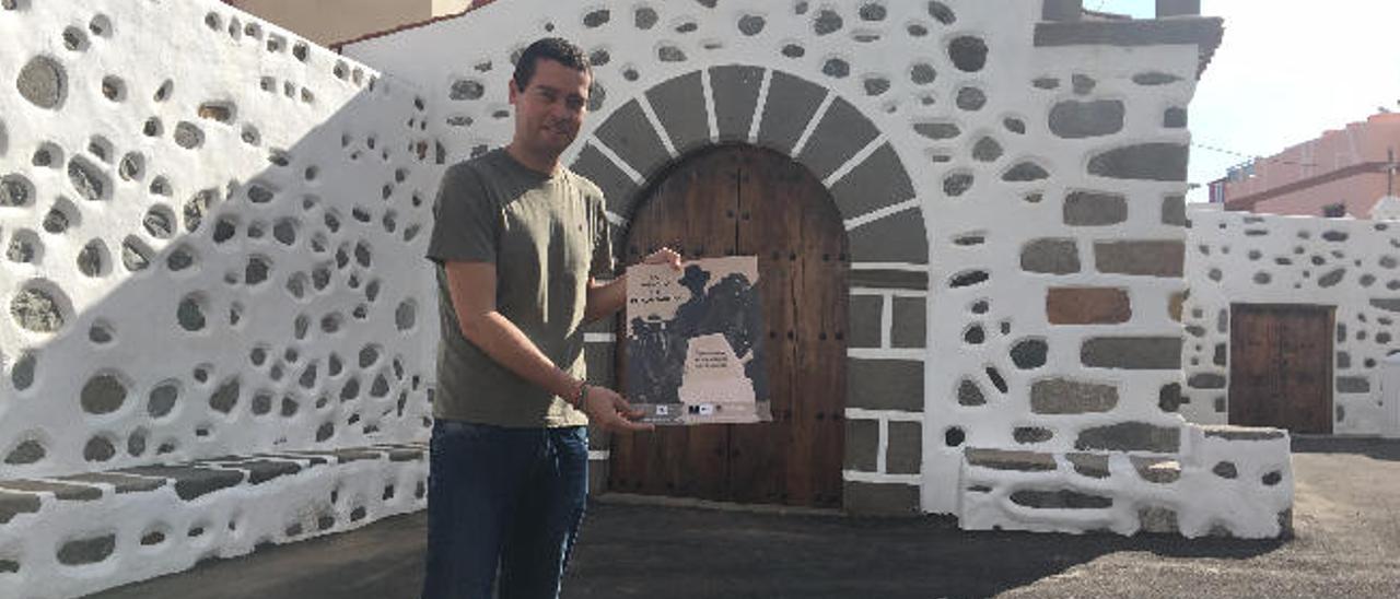 Javier Falcón muestra el cartel de la actividad en la ermita de San Antonio, donde tendrá lugar hoy el acto.