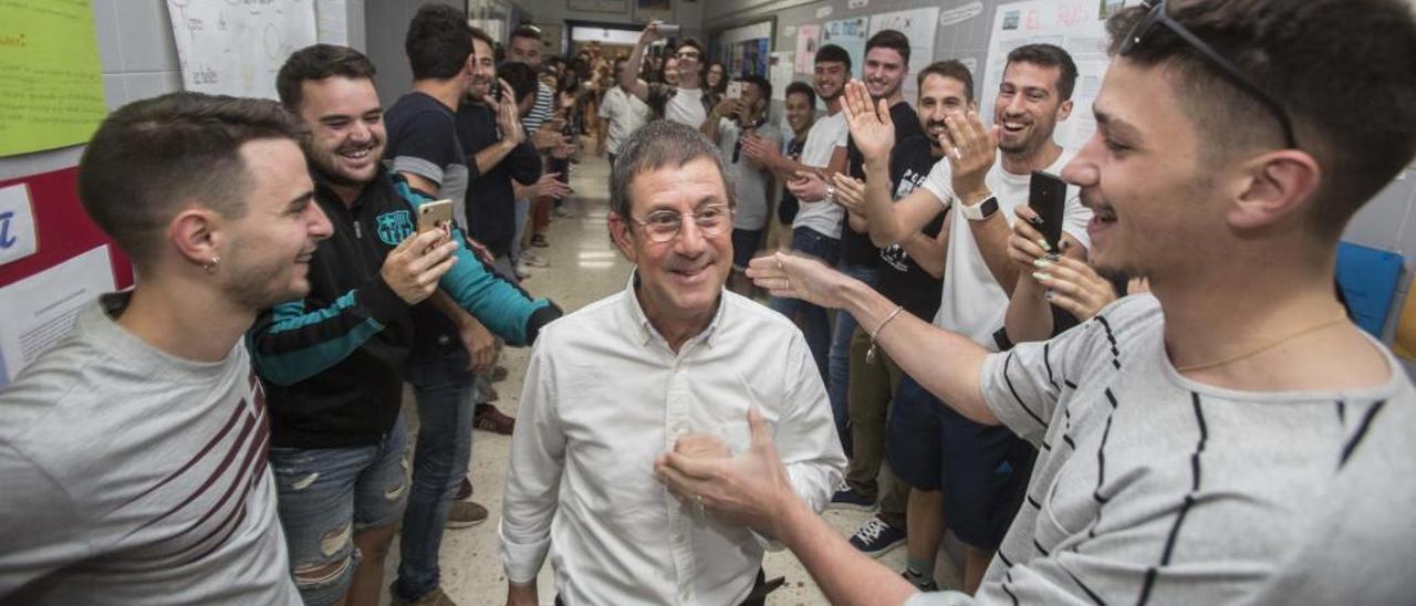 Alumnos de antiguas promociones sorprenden con una despedida a Vicent Berenguer en el pasillo del IES Cabo de la Huerta.