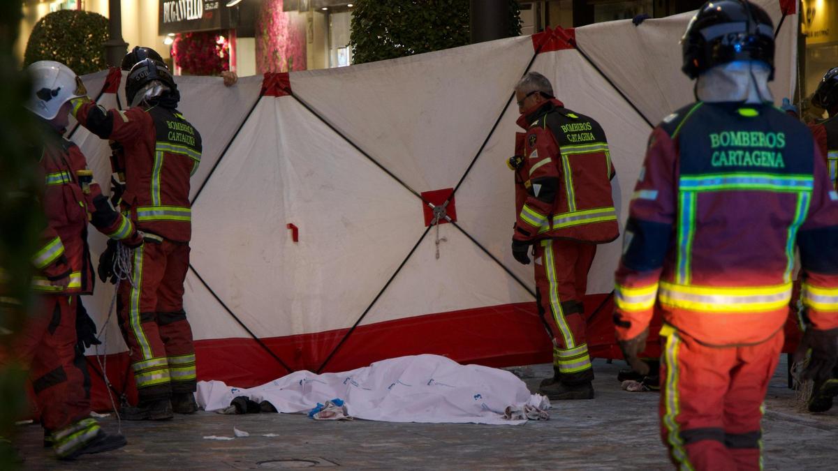 Bomberos cubren el cuerpo sin vida del hombre que se quemó a lo bonzo en la calle Santa Florentina de Cartagena.