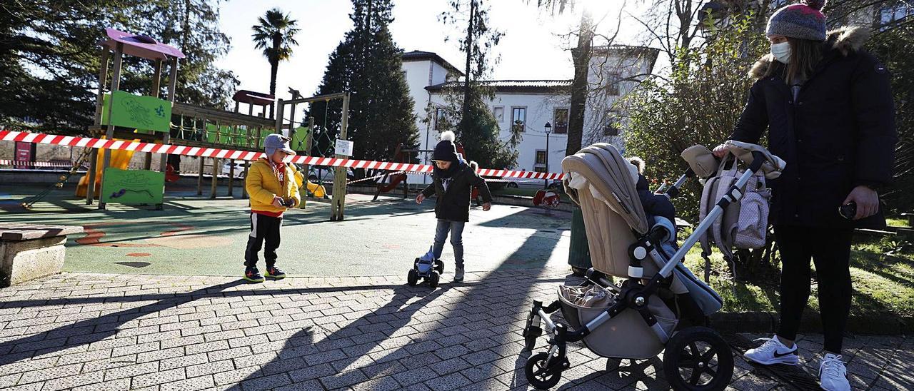 Mateo Cabal y Álvaro Rodríguez juegan en presencia de Laura Granda, con su hijo Nico Cabal en la silla, al lado de un parque de Grado. | Luisma Murias