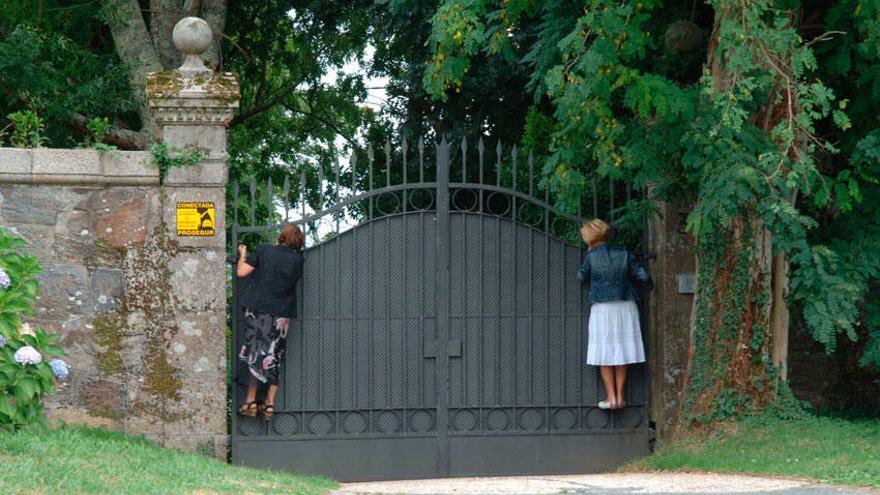 Dos mujeres encaramadas al portalón de entrada del Pazo de Meirás.