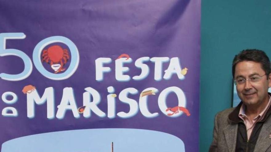 El alcalde, Miguel Pérez, con el cartel que anuncia la próxima Festa do Marisco.  // Muñiz