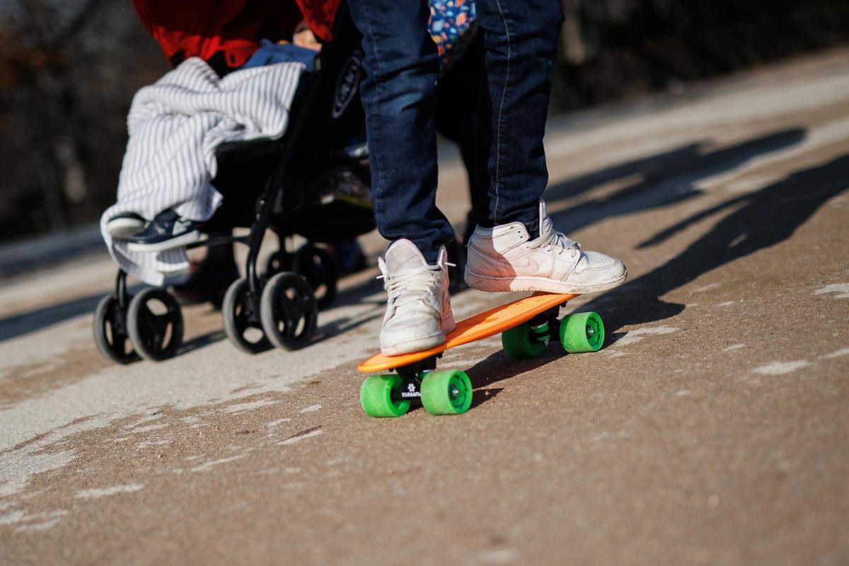 Archivo - Un niño con un patinete pasea por un parque