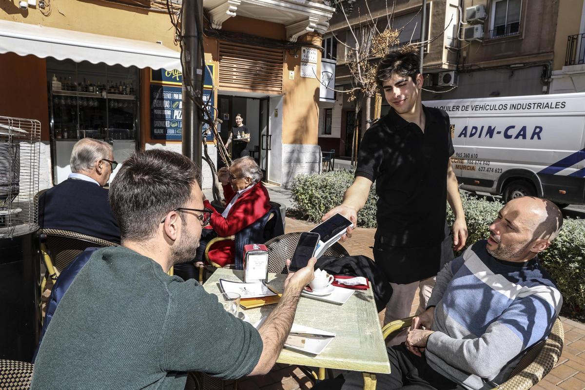 Un cliente paga con su móvil en la Plaza Nueva de Alicante.