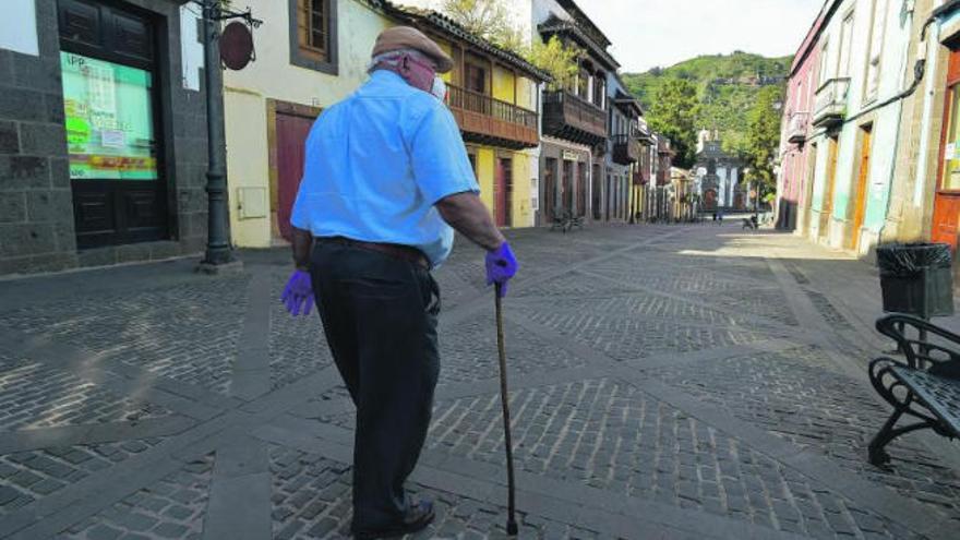 Un pensionista con guantes pasea por la calle principal de Teror.