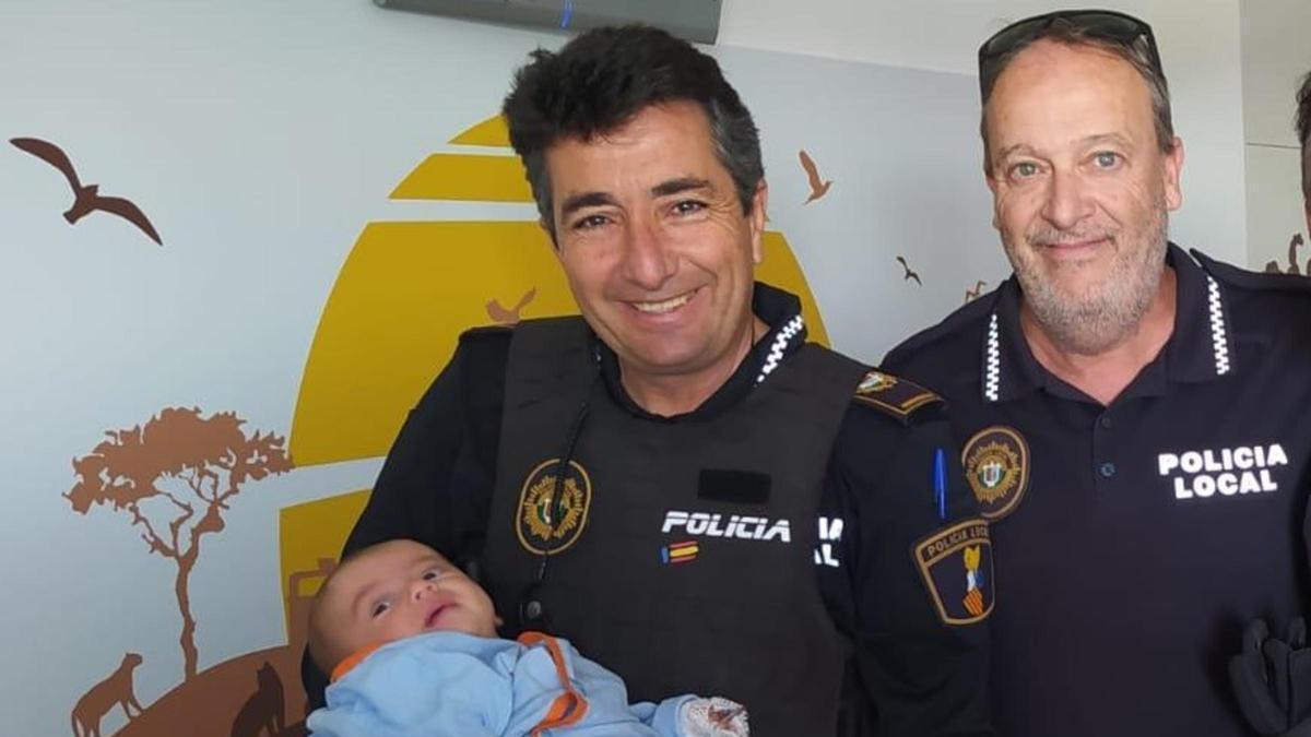 Los dos agentes de Santa Pola posan junto al bebé, la cara de los policías lo dice todo