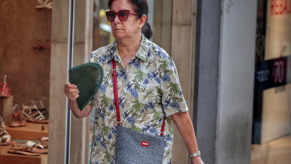 Una mujer se abanica mientras camina por las calles de Santa Cruz para mitigar el calor.