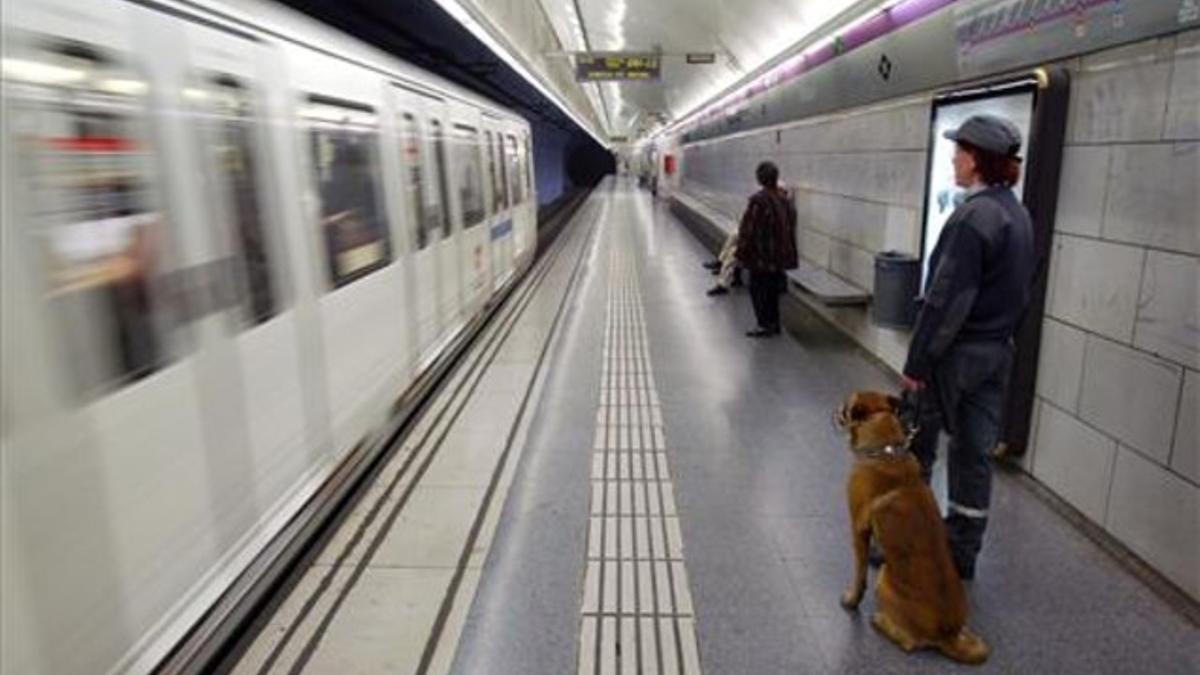 Vigilante con un perro con bozal en el Metro de Barcelona.