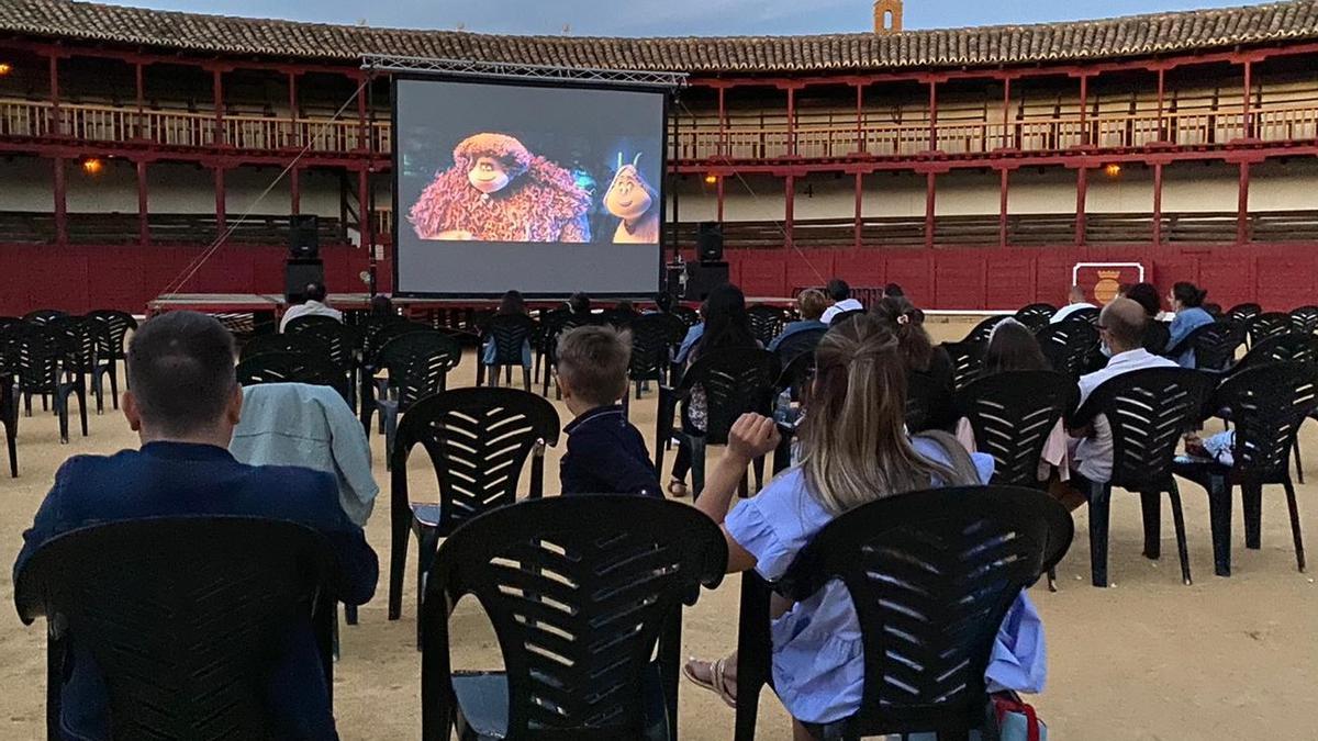 Varias personas disfrutan de una película al aire libre en una plaza de toros