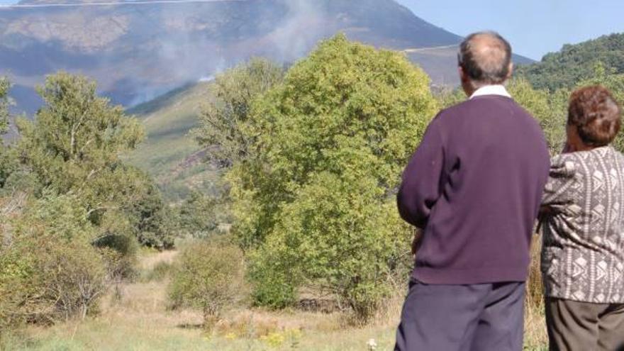 Dos personas observan el incendio declarado el domingo en San Ciprián.