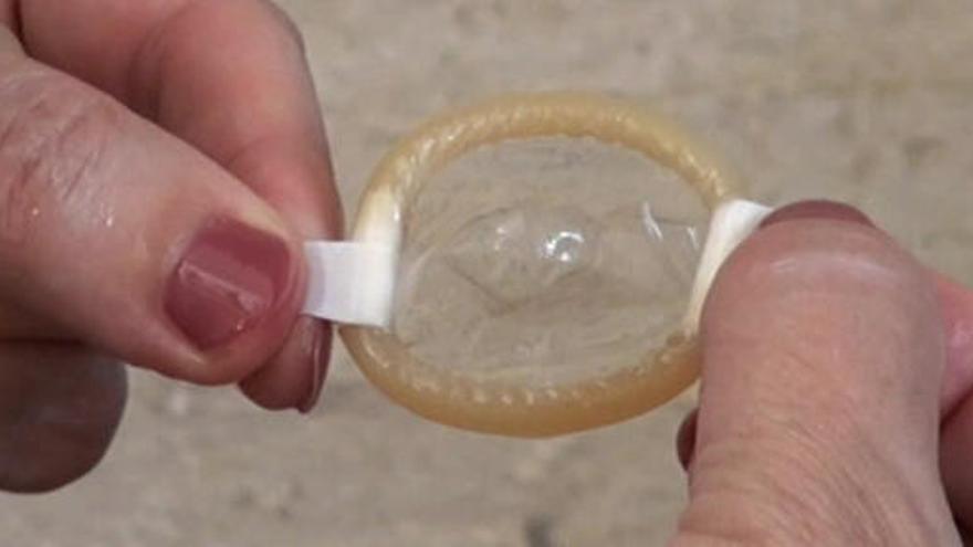 Una joven muestra un preservativo.