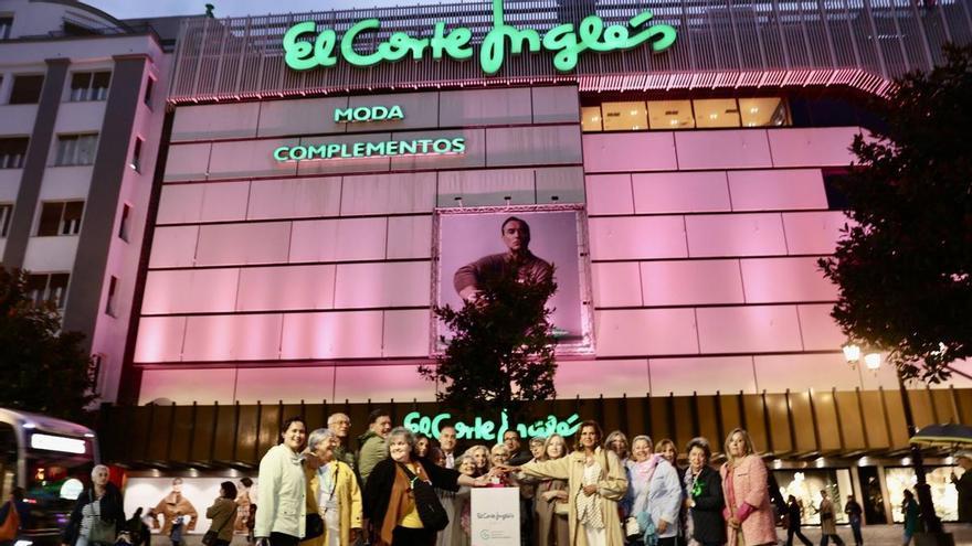 El coro de la AECC y sus voluntarias encienden de rosa la fachada de El Corte Inglés de Oviedo