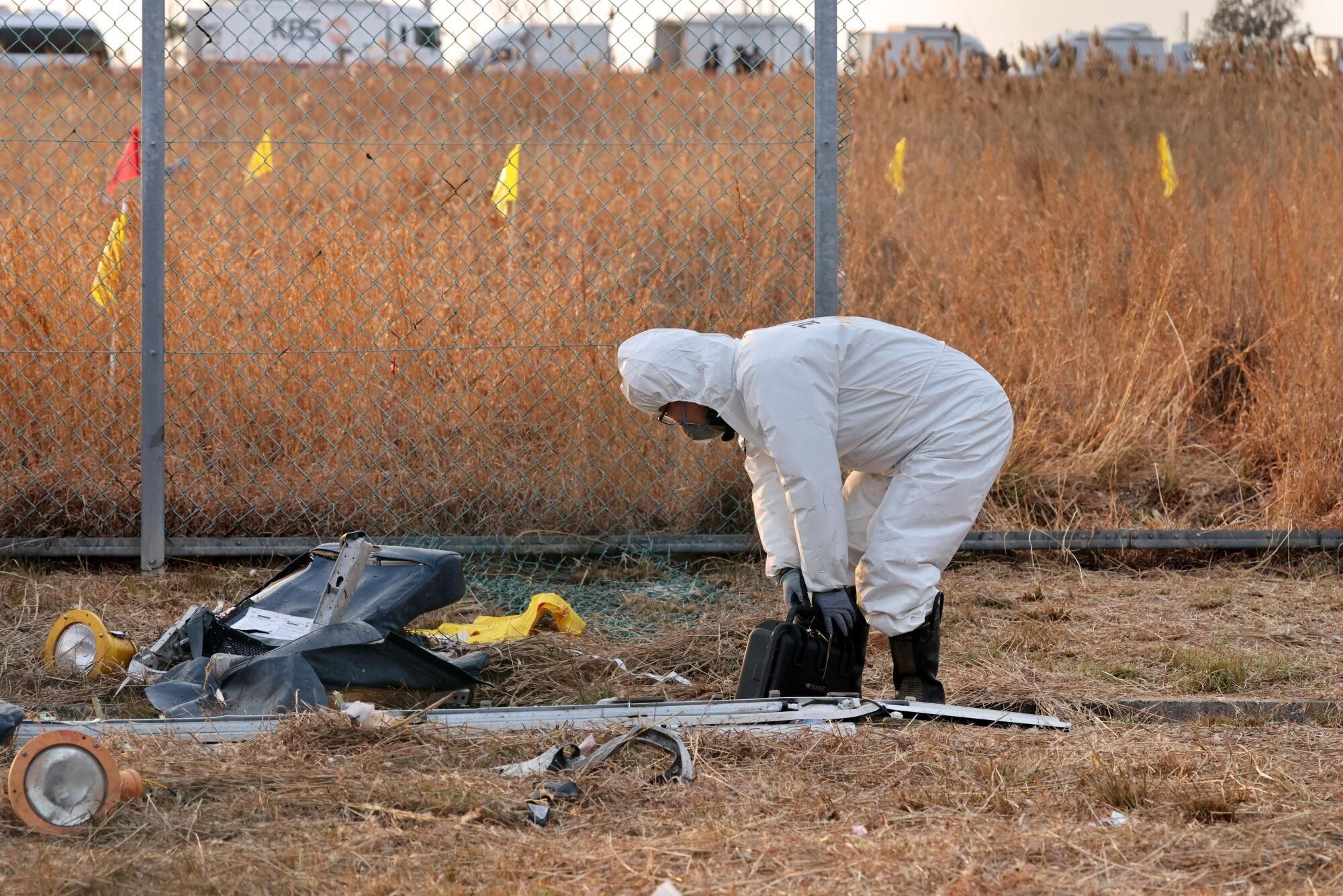 Muan (South Korea), 29/12/2024.- A member of Korea Crime Scene Investigation (KCSI) inspects the wreckage of the Jeju Air aircraft at Muan International Airport in Muan, 288 kilometers southwest of Seoul, South Korea, 29 December 2024. According to the National Fire Agency, a passenger jet carrying 181 people erupted in flames after going off the runway at an airport in South Korea's southwestern county of Muan on 29 December, leaving at least 62 people dead. (Corea del Sur, Seúl) EFE/EPA/HAN MYUNG-GU
